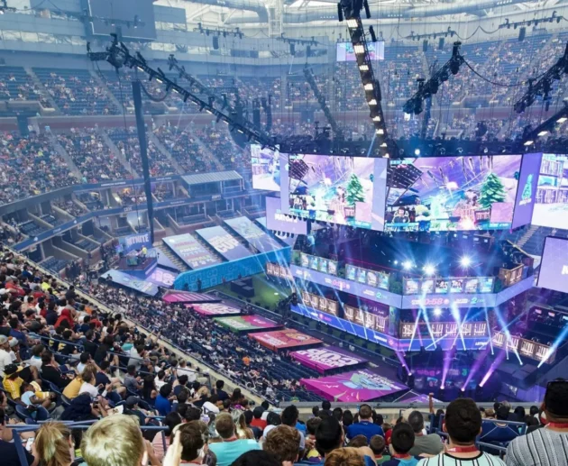 scène d’e-sport dynamique montrant des joueurs sur scène avec des écrans géants, des fans en live, et des graphiques de données et logos de sponsors flottants, symbolisant l’intersection culture, business et technologie