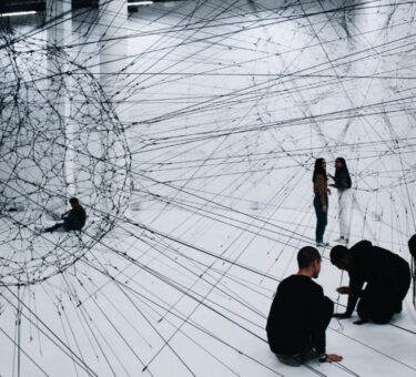 groupe d’artistes et créateurs autour d’une installation immersive, mélangeant écrans, sculptures et dessins, avec des interactions visibles entre participants et technologies numériques