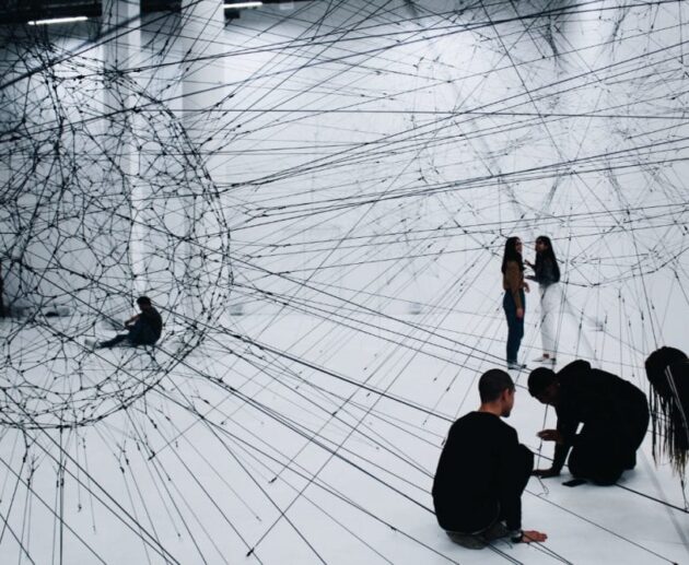 groupe d’artistes et créateurs autour d’une installation immersive, mélangeant écrans, sculptures et dessins, avec des interactions visibles entre participants et technologies numériques